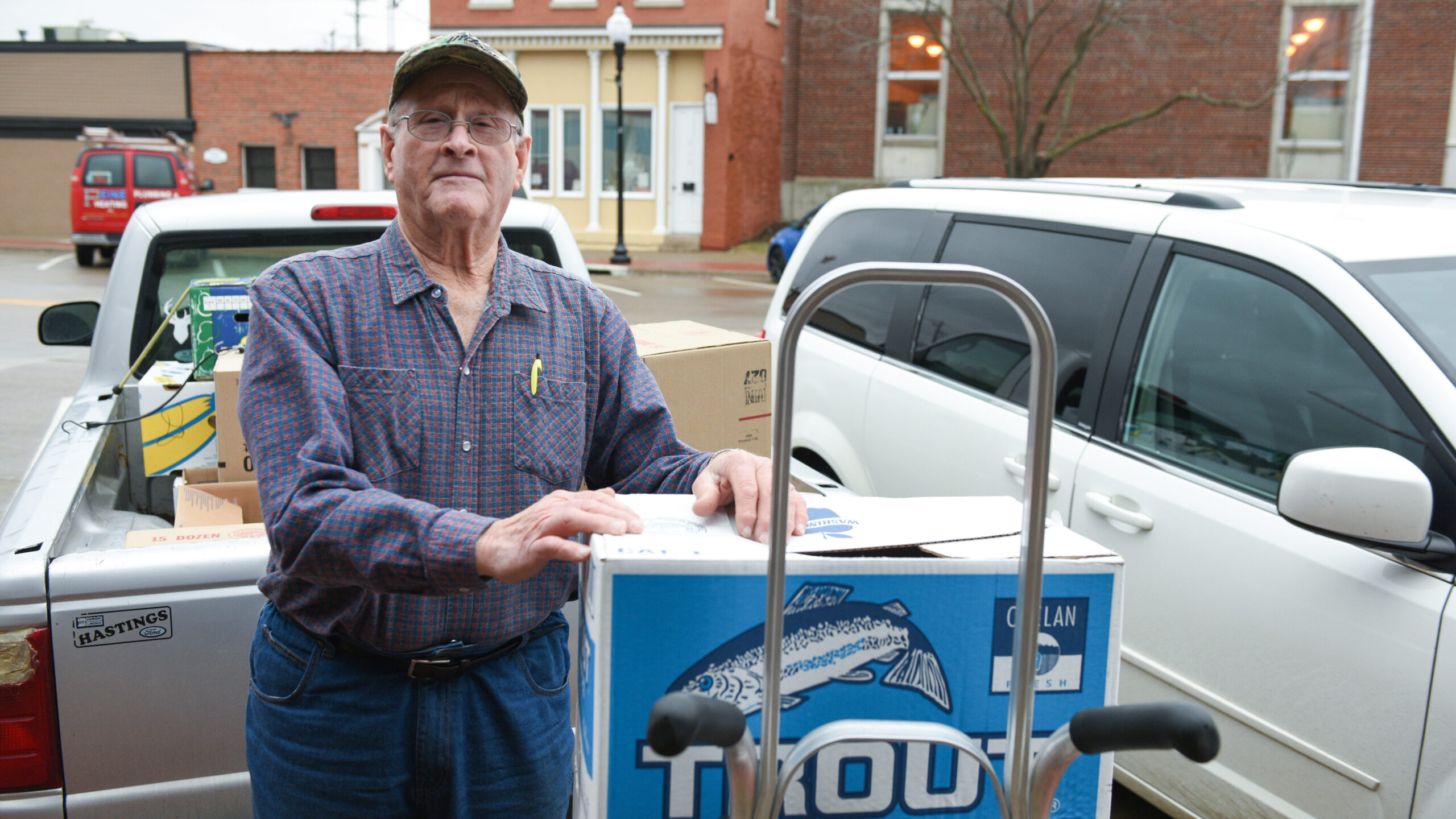 An older adult delivering boxes to a business in a small town