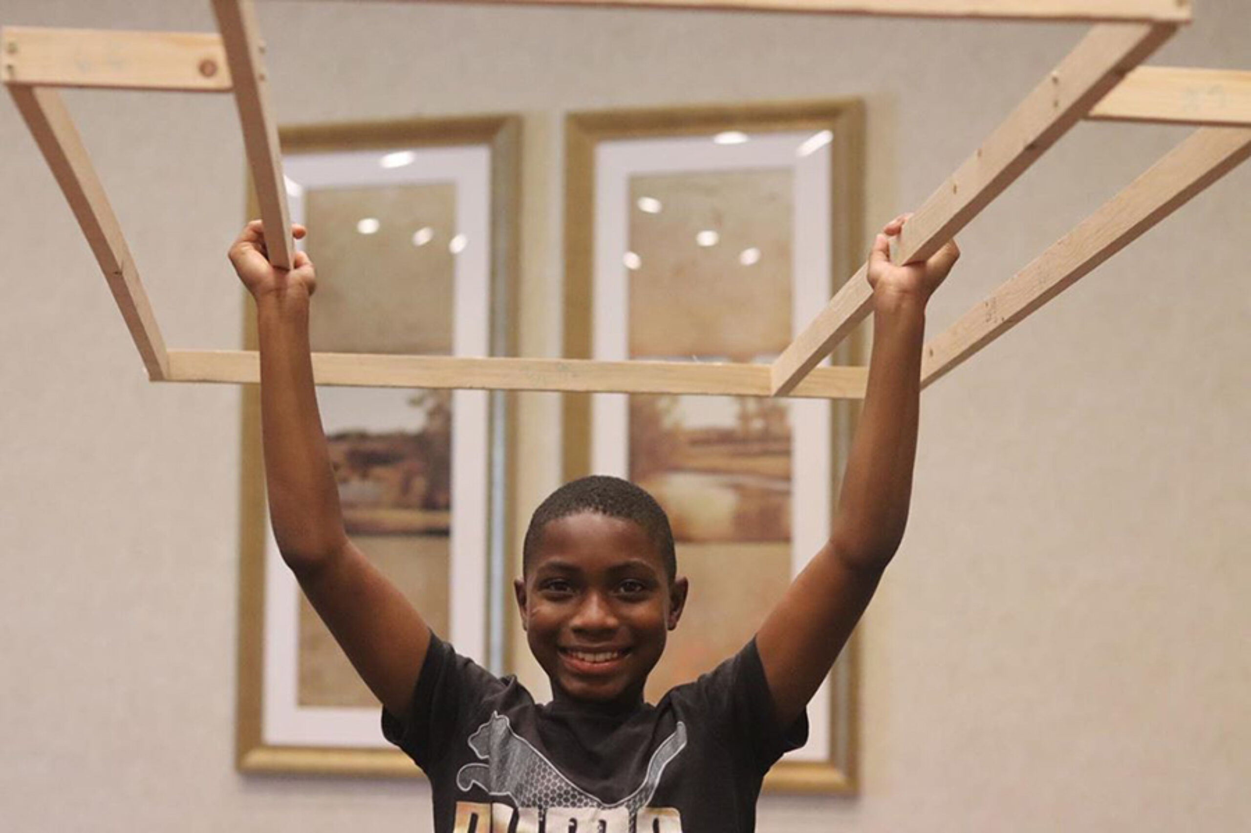 Boy holding up artwork made of wood